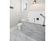 Tiled bathroom with marble accents, a bathtub, and a sleek black faucet at 8175 Main St, Woodstock, GA 30188
