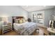 Bright bedroom featuring a queen-sized bed, a wood headboard, and a view to the front yard at 8175 Main St, Woodstock, GA 30188
