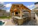 Outdoor kitchen and bar area with a stone counter, stainless steel grill, and a cozy stone fireplace, perfect for entertaining at 8175 Main St, Woodstock, GA 30188