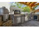 A well-equipped outdoor kitchen features a stainless steel grill, pizza oven, and beverage cooler, ideal for outdoor cooking at 8175 Main St, Woodstock, GA 30188