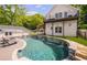 Backyard pool with waterfall features, surrounded by lounge chairs and a covered patio with a kitchen at 8175 Main St, Woodstock, GA 30188