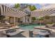 Backyard pool with tanning ledges, surrounded by lounge chairs and covered patios with outdoor seating at 8175 Main St, Woodstock, GA 30188