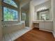 Bright bathroom featuring large window, soaker tub, tiled floors, and walk-in shower at 9454 Lakeview Ct, Douglasville, GA 30135