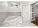Bathroom with white marble tub, window, white floors, and shelved linen closet at 105 Laurel Ridge Ct, Fayetteville, GA 30215