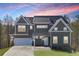 Two-story home featuring neutral siding, a dark roof, white trim, and an attached two-car garage under colorful sky at 3180 Tackett Rd, Douglasville, GA 30135
