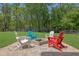 Landscaped backyard with a stone firepit, colorful Adirondack chairs, lush lawn, and wooded surroundings at 326 Carmichael Cir, Canton, GA 30115