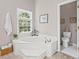 Bright bathroom featuring a soaking tub next to window and an adjacent toilet area at 510 Birch Ridge Ct, Roswell, GA 30076