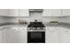 Close-up view of the modern stove, granite countertops, and white cabinets in this renovated kitchen at 5209 Carrington Park Dr, Powder Springs, GA 30127