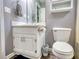 Bathroom offers vanity with storage, framed mirror, neutral wall color, dark flooring, toilet, and cabinet at 70 Summer Walk Dr, Covington, GA 30016