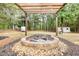 Fire pit area with brick surround, stone ground cover, a wooden pergola, and mature trees at 70 Summer Walk Dr, Covington, GA 30016