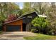 Contemporary home featuring black and wood siding, attached garage, and beautifully landscaped yard with mature trees at 4727 Emily Sw Dr, Lilburn, GA 30047