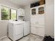 Bright laundry room with modern washer, dryer, storage cabinets, and a window with outdoor view at 4727 Emily Sw Dr, Lilburn, GA 30047