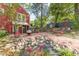 Backyard with red brick patio and walkway showcases lush greenery, rock features, and cozy seating areas for relaxing outdoors at 2733 Winburn Ter, East Point, GA 30344