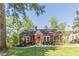 Charming red home featuring a manicured lawn, landscaping, and a welcoming yellow front door at 2733 Winburn Ter, East Point, GA 30344