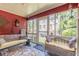 Cozy sunroom with red walls features a swing, wicker seating, and large windows, offering a bright and relaxing space at 2733 Winburn Ter, East Point, GA 30344