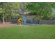 Charming backyard playhouse with a slide and swingset, set against a backdrop of mature trees and green lawn at 3935 Manor House Dr, Marietta, GA 30062