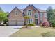 Charming two-story brick home featuring a well-manicured lawn, dual garage, and elegant arched windows at 1315 Chattahoochee Run Dr, Suwanee, GA 30024