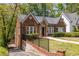 Charming brick home with stone entryway, decorative windows, lush lawn, and black iron fence at 1900 Ridgewood Ne Dr, Atlanta, GA 30307