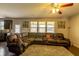 Comfortable living room with a ceiling fan, large windows, and a sizable brown leather sectional couch at 375 Madison Grace Ave, Mcdonough, GA 30252