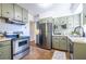 Well-lit kitchen with stainless steel appliances, sage green cabinets, and tile flooring at 1740 Fairbanks Sw St, Atlanta, GA 30310