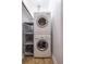 Compact laundry area with stacked washer and dryer unit and storage shelves at 1740 Fairbanks Sw St, Atlanta, GA 30310