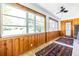 Light-filled sunroom featuring wood paneled walls, white ceiling, and a ceiling fan at 1740 Fairbanks Sw St, Atlanta, GA 30310