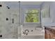 Bright bathroom with a glass-enclosed shower, soaking tub, and a window providing natural light at 5108 Staplehurst Ln, Woodstock, GA 30189