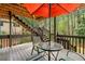 Inviting back deck with stairs, outdoor seating, and a vibrant orange umbrella overlooking a lush green, wooded backyard at 3522 Evans Ridge Trl, Atlanta, GA 30340