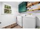 Clean laundry room with modern washer and dryer, green cabinets, open shelving, and wood-look flooring at 3522 Evans Ridge Trl, Atlanta, GA 30340