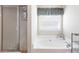Bright bathroom featuring a soaking tub next to a window and a separate glass-enclosed shower area at 981 Golden Meadows Ln, Loganville, GA 30052