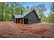 Rear angled view of the home featuring a covered porch with natural wood posts and dark exterior siding at 1687 Harmony Rd, Temple, GA 30179
