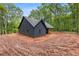 Rear angled view of the home featuring a covered porch with natural wood posts and dark exterior siding at 1687 Harmony Rd, Temple, GA 30179