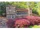 Stone community sign for The Flats at Riverwalk, surrounded by vibrant landscaping at 1910 Cedar Glenn Way # 4104, Atlanta, GA 30339