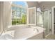 Bright bathroom features a large garden tub with a view of the outdoors and a glass enclosed shower at 2012 Golfers Way, Villa Rica, GA 30180
