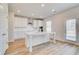 Bright kitchen features wood flooring, stainless steel appliances, white cabinets and a kitchen island at 612 Leafy Branch Way, Mcdonough, GA 30253