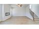 Spacious living room with cozy fireplace, neutral walls, ceiling fan, and stairs leading to the upper level at 612 Leafy Branch Way, Mcdonough, GA 30253