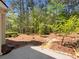 View of the landscaped backyard with mature trees and a concrete patio at 956 Buckhorn Bnd, Locust Grove, GA 30248