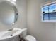Powder room with a round mirror, a pedestal sink and a window allowing natural light at 956 Buckhorn Bnd, Locust Grove, GA 30248
