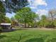 Expansive backyard with a large grassy area, mature trees, and stone retaining wall at 1102 Emory St, Oxford, GA 30054