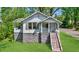 Charming home features a stone foundation, neutral siding and inviting front porch, nestled among mature trees at 1685 Carroll Nw Dr, Atlanta, GA 30318