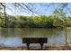 Scenic lake view with a wooden bench overlooking the water and lush greenery, perfect for relaxation and enjoying nature at 1438 Sutters Pond Nw Dr, Kennesaw, GA 30152