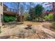 Brick patio with a fire pit and seating area, surrounded by lush greenery and mature trees at 317 Vista Lake Dr, Suwanee, GA 30024