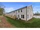 Back exterior view of new townhomes with grassy lawn, wooden fence, and outdoor patio set on a sunny day at 425 Brooch Way, Stockbridge, GA 30281