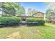 Back exterior featuring mature trees, manicured hedges, and green grass at 951 Woodmont Dr, Marietta, GA 30062