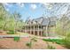 Home featuring a covered porch, dormer windows, stone accents, lush green landscaping, and an attached three-car garage at 18 Crolley Ln, White, GA 30184