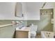 Well-lit bathroom with green tiling, a white sink, and a white toilet at 5295 Woodland Dr, Lake City, GA 30260