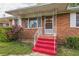 Charming brick home featuring a welcoming front entrance with red steps and ornate white railing at 5295 Woodland Dr, Lake City, GA 30260