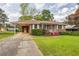 Charming brick home featuring a well-maintained lawn, covered carport, and landscaped front yard at 5295 Woodland Dr, Lake City, GA 30260