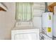 Functional laundry area with washer, shelving, and water heater for efficient home maintenance at 5295 Woodland Dr, Lake City, GA 30260