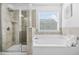 Bright bathroom featuring a separate shower and a soaking tub beneath a window at 7691 Cabrini Pl, Fairburn, GA 30213